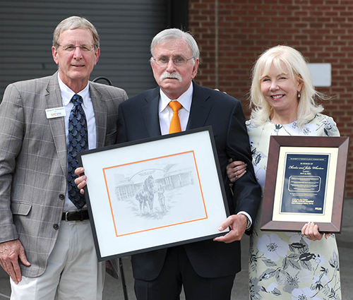 (Left) Honoring Charles and Julie Wharton at the renaming ceremony for the Charles and Julie Wharton Large Animal Hospital in 2022, Jim Thompson presents a plaque and artwork to Charles and Lori Wharton.