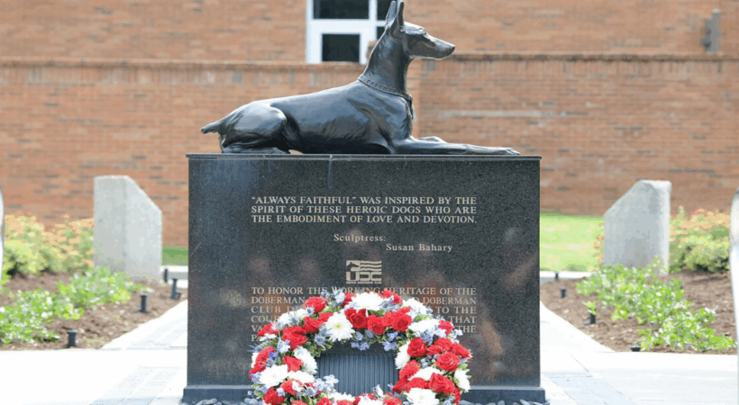 A red, white, and blue floral wreath lays at the foot of the War Dog Memorial located in front of the University of Tennessee College of Veterinary Medicine.