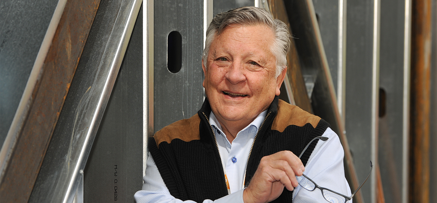 Dr. Robert DeNova posing in front of a fence.
